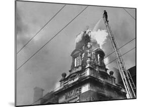 Fireman on Ladder Using a Hose to Extinguish Blazing Building Set Afire-Hans Wild-Mounted Photographic Print