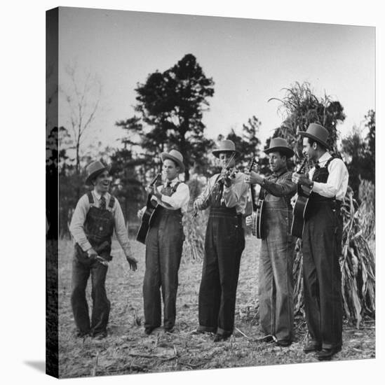 Five Male Musicians Dressed in Hats and Bib Overalls Standing in a Field-Eric Schaal-Stretched Canvas