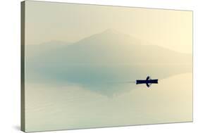 Fog over the Lake. Silhouette of Mountains in the Background. the Man Floats in a Boat with a Paddl-Maryna Patzen-Stretched Canvas