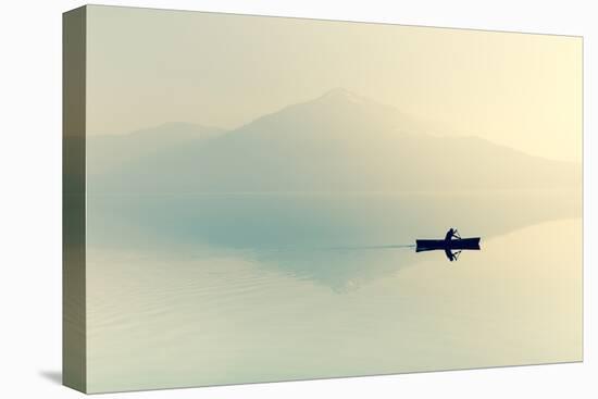 Fog over the Lake. Silhouette of Mountains in the Background. the Man Floats in a Boat with a Paddl-Maryna Patzen-Stretched Canvas