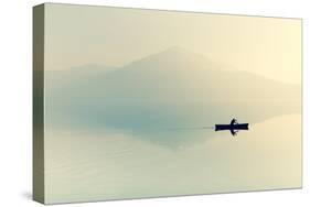Fog over the Lake. Silhouette of Mountains in the Background. the Man Floats in a Boat with a Paddl-Maryna Patzen-Stretched Canvas