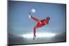Football Player in Red Kicking against Large Football Stadium with Spotlights under Grey Sky-Wavebreak Media Ltd-Mounted Photographic Print