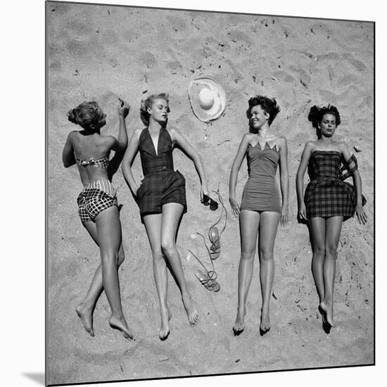 Four Models Showing Off the Latest Bathing Suit Fashions While Lying on a Sandy Florida Beach-Nina Leen-Mounted Photographic Print