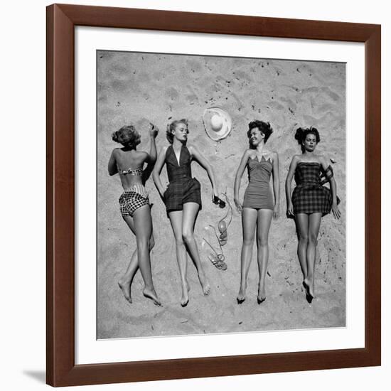 Four Models Showing Off the Latest Bathing Suit Fashions While Lying on a Sandy Florida Beach-Nina Leen-Framed Photographic Print