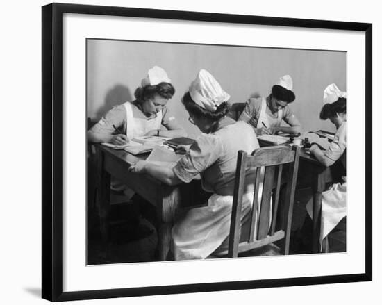 Four Young British Student Nurses Making Notes Together from Medical Textbooks-null-Framed Photographic Print