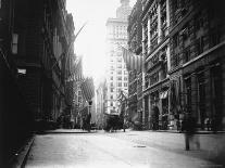 People and Horse Drawn Carts on Wall St, Where American Flags Fly from Buildings-George B^ Brainerd-Laminated Photographic Print