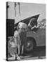 Girl Attendant Looking For Battery For Customer-Allan Grant-Stretched Canvas