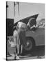 Girl Attendant Looking For Battery For Customer-Allan Grant-Stretched Canvas