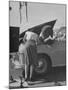 Girl Attendant Looking For Battery For Customer-Allan Grant-Mounted Photographic Print