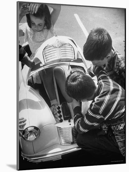 Girl Demurely Adjusting Her Hair While Willing Volunteers Repair Jammed Front Wheels of Her Car-Nina Leen-Mounted Photographic Print