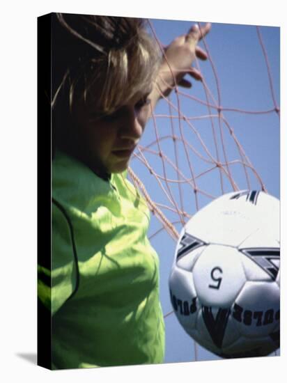 Girl Standing in a Goal Looking at a Soccer Ball-null-Stretched Canvas