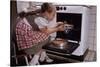 Girl Wearing Apron Removing Cakes from Oven-William P. Gottlieb-Stretched Canvas