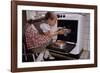 Girl Wearing Apron Removing Cakes from Oven-William P. Gottlieb-Framed Photographic Print