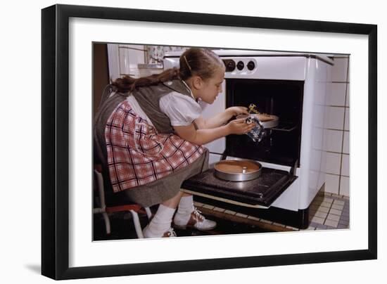 Girl Wearing Apron Removing Cakes from Oven-William P. Gottlieb-Framed Photographic Print