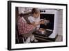 Girl Wearing Apron Removing Cakes from Oven-William P. Gottlieb-Framed Photographic Print