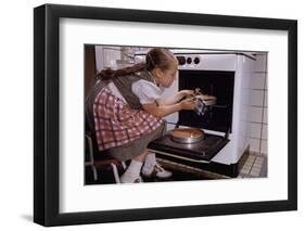 Girl Wearing Apron Removing Cakes from Oven-William P. Gottlieb-Framed Photographic Print