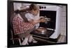 Girl Wearing Apron Removing Cakes from Oven-William P. Gottlieb-Framed Photographic Print