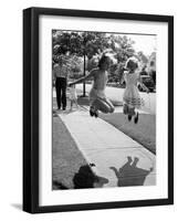 Girls on the street in neighborhood using rope to jump in tandem while man with toddler watches-Alfred Eisenstaedt-Framed Photographic Print