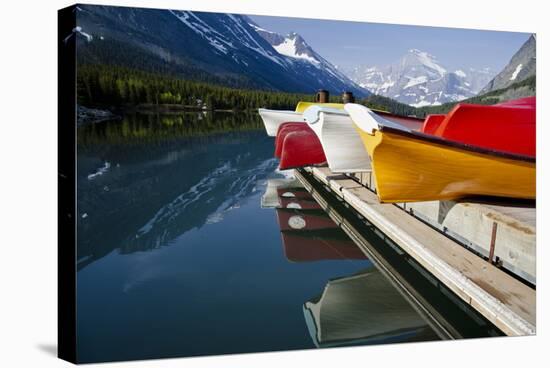 Glacier, Montana: Colorful Canoes Line the Dock at Many Glacier Lodge on Swiftcurrent Lake-Brad Beck-Stretched Canvas