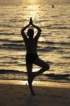 Woman practising yoga meditation on beach at sunset as concept for silence and relaxation-Godong-Photographic Print