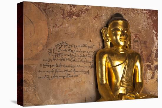 Golden Buddha Statue in Front of Burmese Writing on Wall, Bagan, Myanmar-Harry Marx-Stretched Canvas