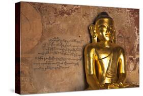 Golden Buddha Statue in Front of Burmese Writing on Wall, Bagan, Myanmar-Harry Marx-Stretched Canvas