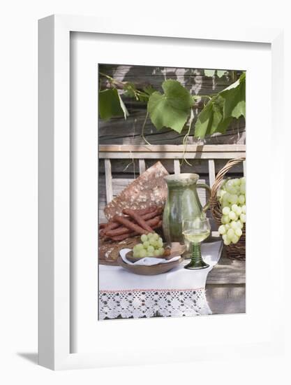 Grapes, Bread, Sausages and Wine on Wooden Bench in Front of Farmhouse-Eising Studio - Food Photo and Video-Framed Photographic Print