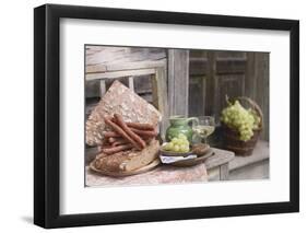 Grapes, Bread, Sausages and Wine on Wooden Bench in Front of Farmhouse-Eising Studio - Food Photo and Video-Framed Photographic Print