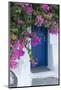 Greece, Santorini. A picturesque blue door is surrounded by pink bougainvillea in Firostefani.-Brenda Tharp-Mounted Photographic Print