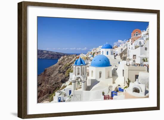 Greek Church with Three Blue Domes in the Village of Oia-Neale Clark-Framed Photographic Print