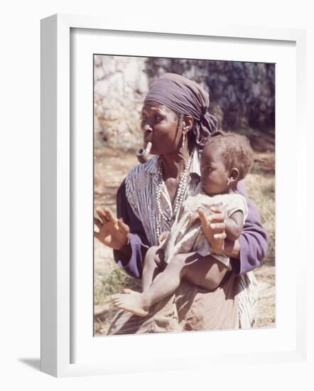 Haitian Woman Smoking a Pipe while Holding a Baby-Lynn Pelham-Framed Photographic Print