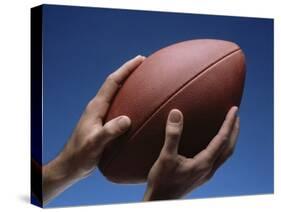 Hands Holding Football with Blue Background-null-Stretched Canvas