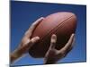 Hands Holding Football with Blue Background-null-Mounted Photographic Print