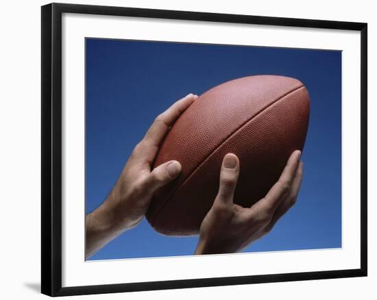 Hands Holding Football with Blue Background-null-Framed Photographic Print