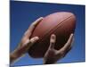 Hands Holding Football with Blue Background-null-Mounted Photographic Print