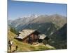 Hiker and Dog on Trail in Front of Traditional Slate Roofed House, Valais, Switzerland-Christian Kober-Mounted Photographic Print