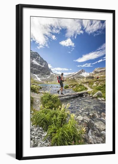 Hiker crossing a stream Engadine Canton of Grisons Switzerland Europe-ClickAlps-Framed Photographic Print