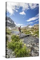 Hiker crossing a stream Engadine Canton of Grisons Switzerland Europe-ClickAlps-Stretched Canvas