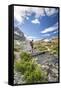 Hiker crossing a stream Engadine Canton of Grisons Switzerland Europe-ClickAlps-Framed Stretched Canvas