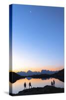 Hikers admiring Brenta Group Dolomites reflected in Lago Nero di Cornisello at dawn-Roberto Moiola-Stretched Canvas