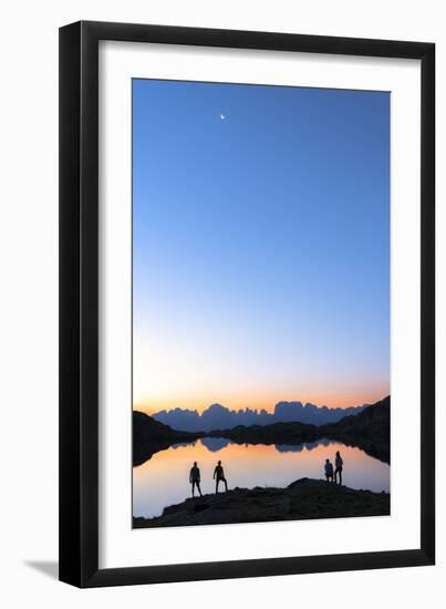 Hikers admiring Brenta Group Dolomites reflected in Lago Nero di Cornisello at dawn-Roberto Moiola-Framed Photographic Print