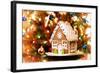 Homemade Christmas Gingerbread House Displayed on a Table. Christmas Tree Lights in the Background.-Leena Robinson-Framed Photographic Print