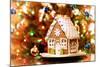 Homemade Christmas Gingerbread House Displayed on a Table. Christmas Tree Lights in the Background.-Leena Robinson-Mounted Photographic Print