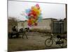 Horse Drawn Cart Drives Past as Balloons Tied to a Bicycle Flutter in the Wind-null-Mounted Photographic Print