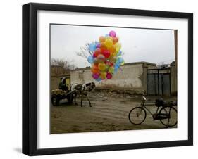 Horse Drawn Cart Drives Past as Balloons Tied to a Bicycle Flutter in the Wind-null-Framed Photographic Print