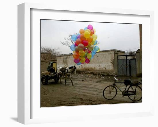 Horse Drawn Cart Drives Past as Balloons Tied to a Bicycle Flutter in the Wind-null-Framed Photographic Print