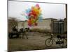 Horse Drawn Cart Drives Past as Balloons Tied to a Bicycle Flutter in the Wind-null-Mounted Photographic Print