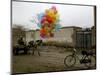 Horse Drawn Cart Drives Past as Balloons Tied to a Bicycle Flutter in the Wind-null-Mounted Photographic Print