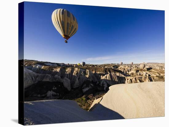 Hot Air Balloons Flying Among Rock Formations at Sunrise in the Red Valley-Ben Pipe-Stretched Canvas