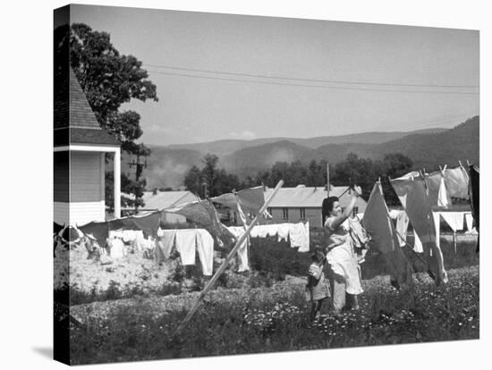 Housewife in Tygart Valley Removing Laundry from Clothesline, Her Young Daughter Stands Beside Her-Carl Mydans-Stretched Canvas